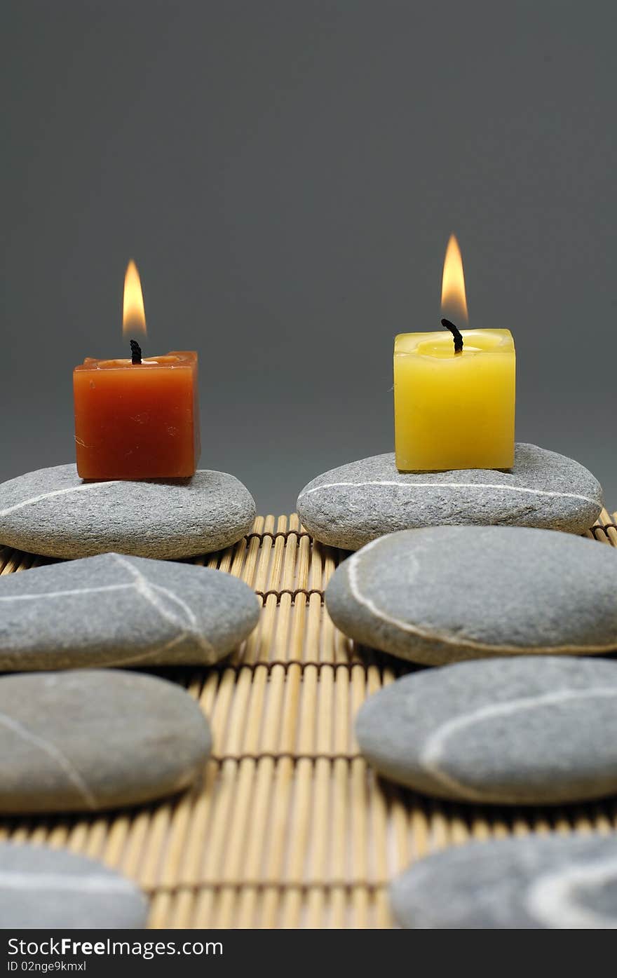 Row of colorful alight candle on zen stones. Row of colorful alight candle on zen stones