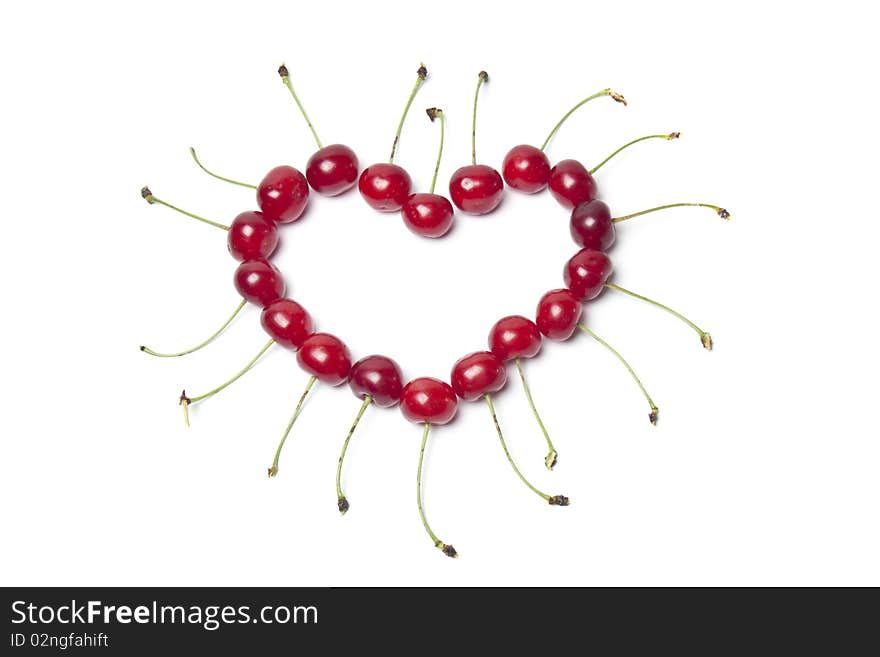 Heart of fresh cherries on a white background