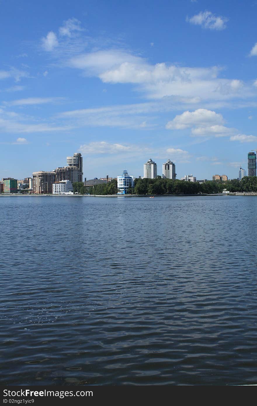 Blue sky and the dark river on a background of modern buildings. Blue sky and the dark river on a background of modern buildings