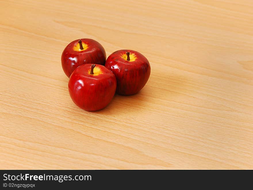 Three red apples on a wooden background