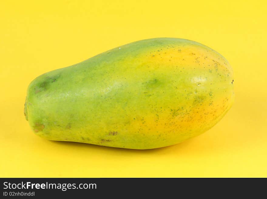 Single Papaya fruit isolated on a yellow background.