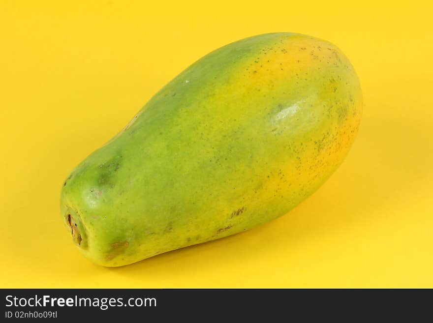 Single Papaya fruit isolated on a yellow background.