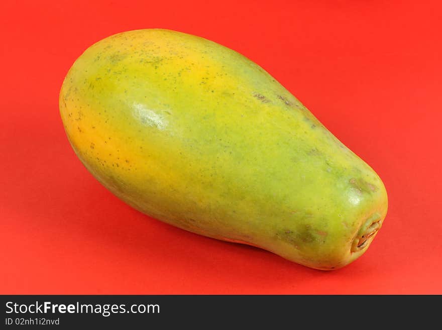 Single Papaya fruit isolated on a red background.