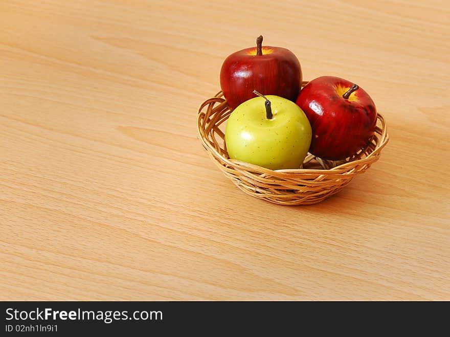 An apple basket with two red and one green apple