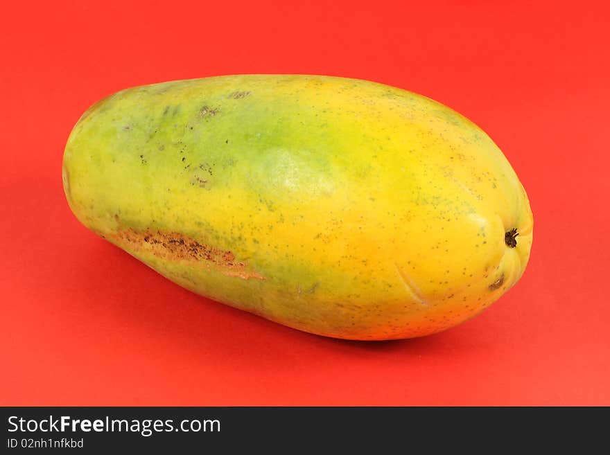 Single Papaya fruit isolated on a red background.