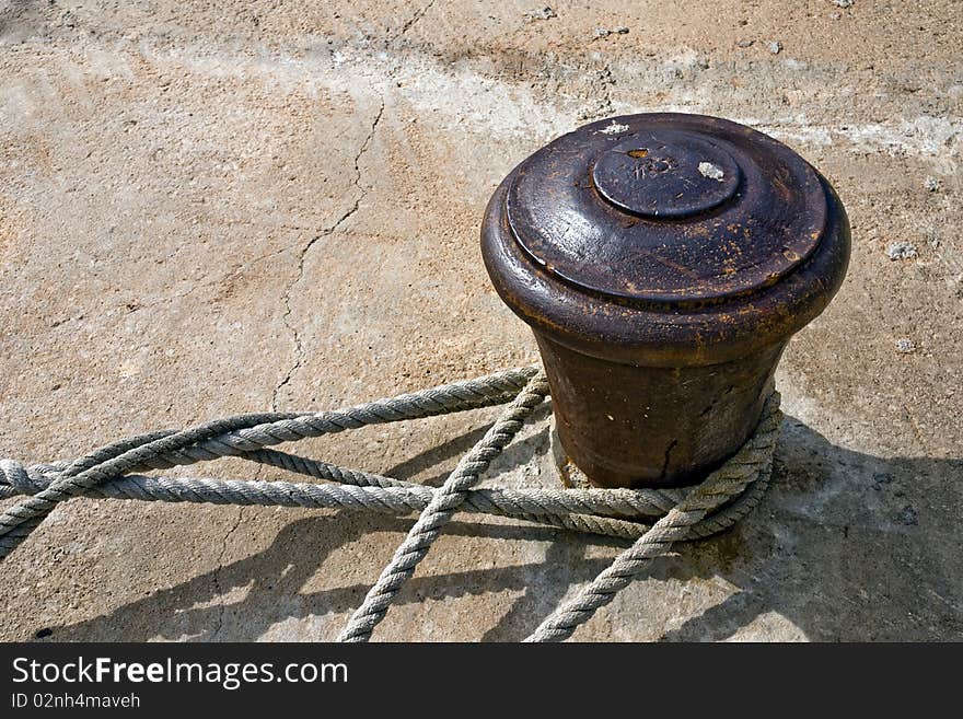 Old rusty bollard with ropes