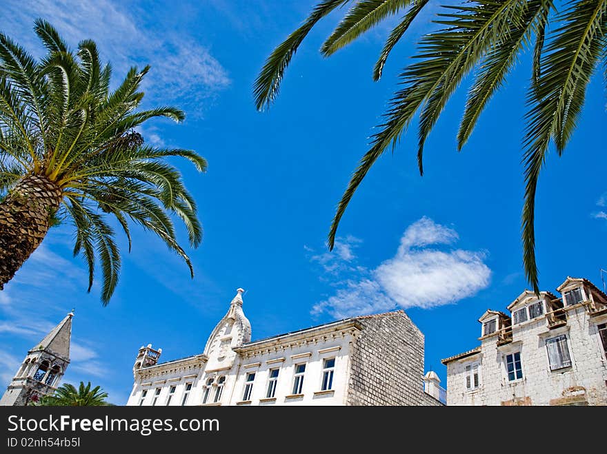 Mediterranean architecture in city of Trogir, Croatia with palm trees and blue sky in the background