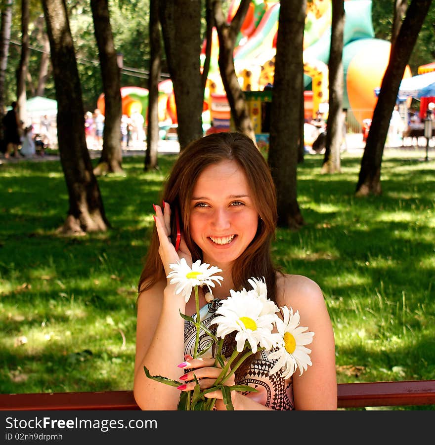 Young pretty female in solar urban park give charming smile beloved speak phone. Young pretty female in solar urban park give charming smile beloved speak phone