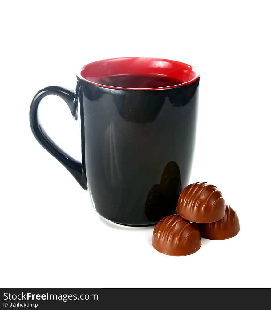 Coffee is in a black cup and chocolate candies isolated on white background