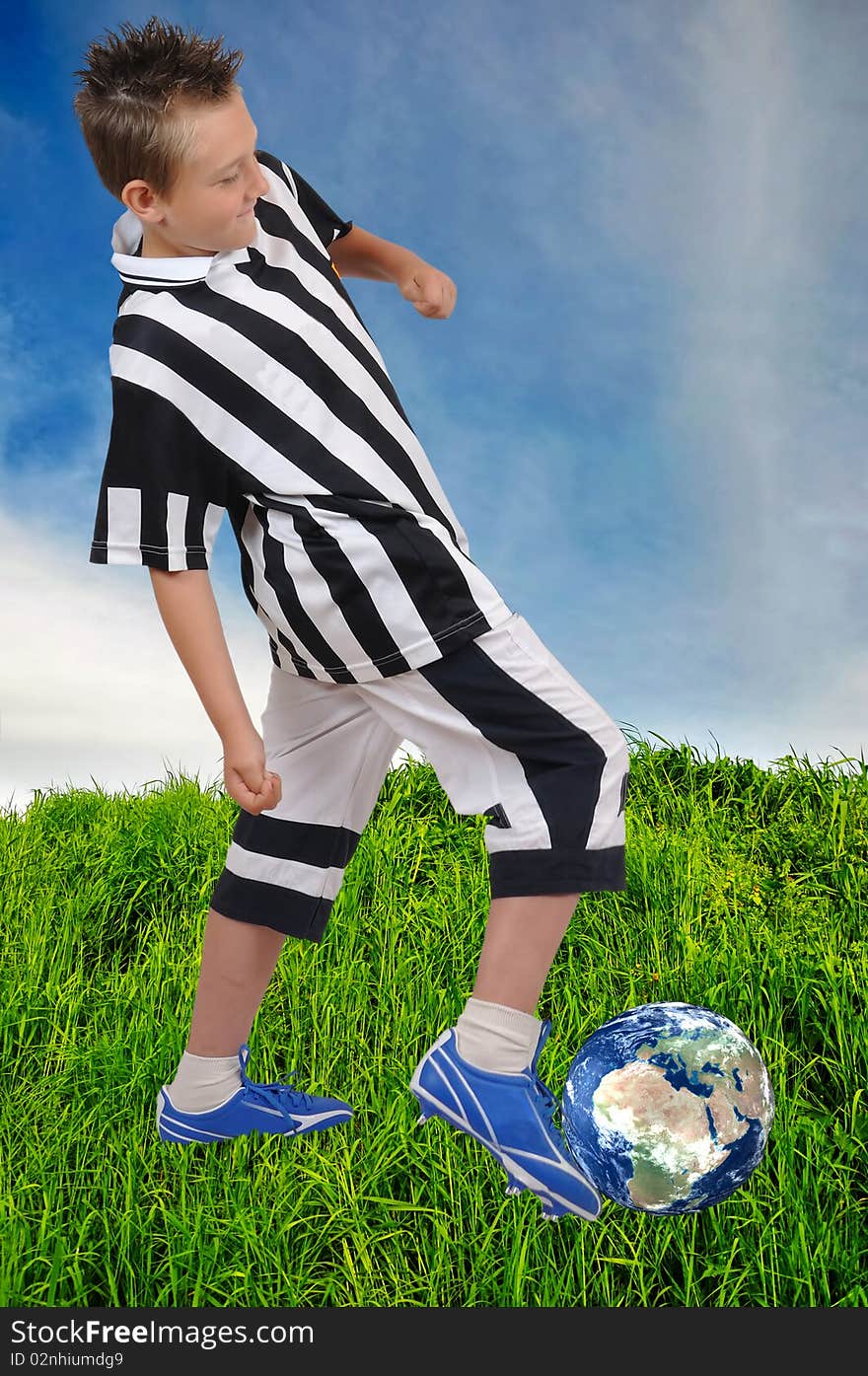 Young footballer with Earth ball on grass