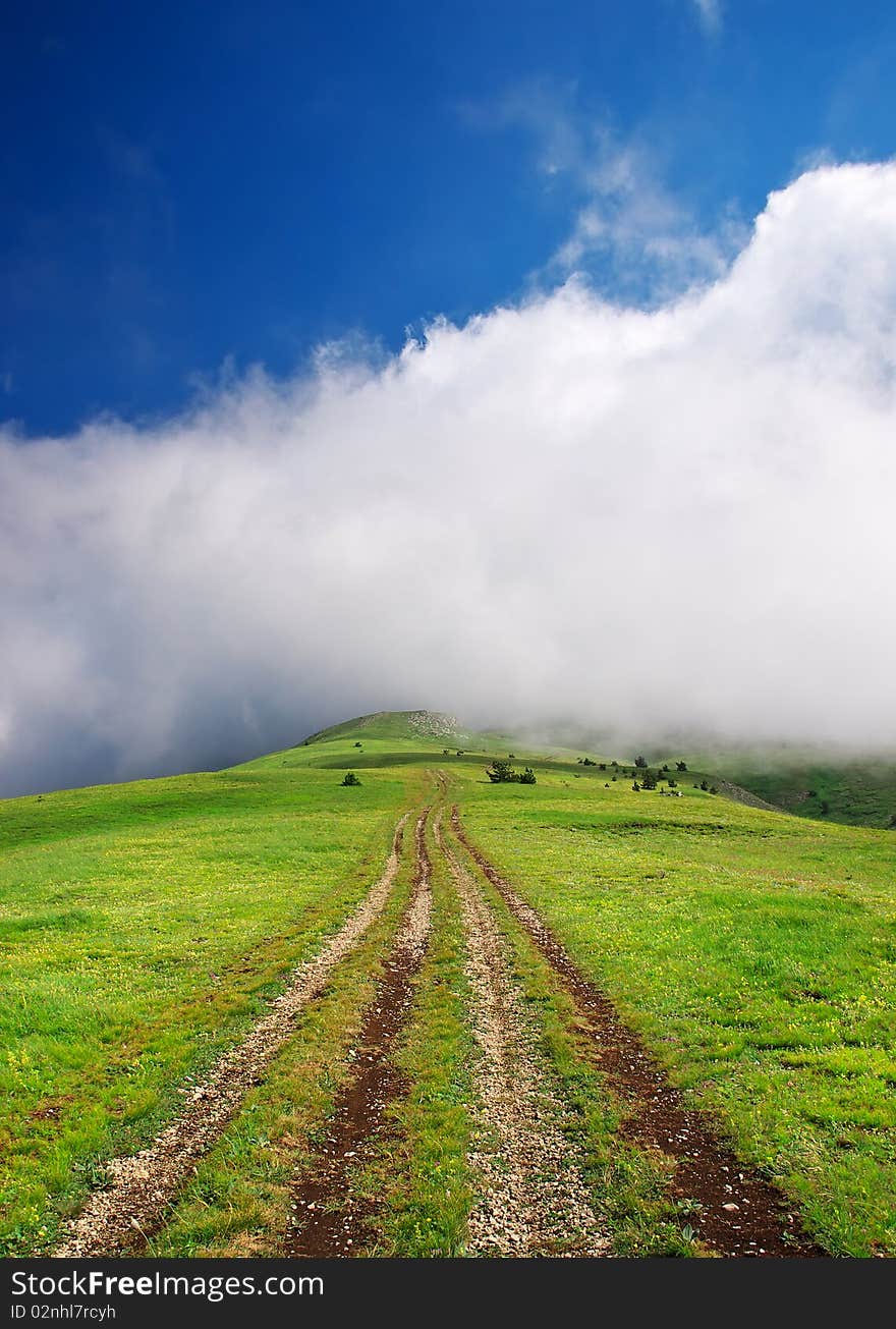 Road on hill leaves in cloud on horizon.