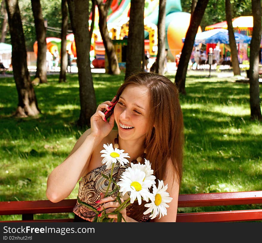 Young pretty female in solar urban park give charming smile beloved speak phone. Young pretty female in solar urban park give charming smile beloved speak phone