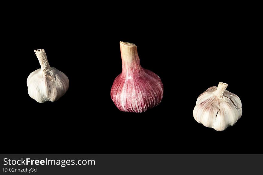 Three heads of garlic on black background