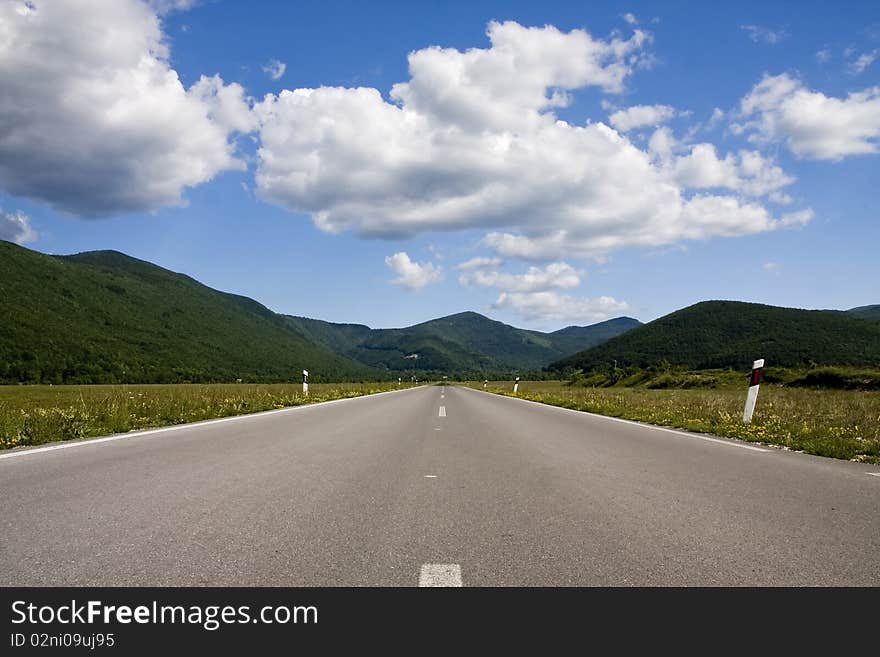 An empty road leading to the mountains in distance.