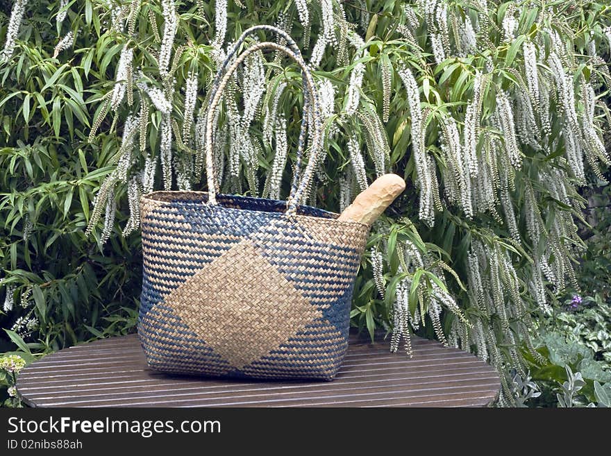 Crispy bread in a wicker shopping basket left on a table in a graden. Crispy bread in a wicker shopping basket left on a table in a graden