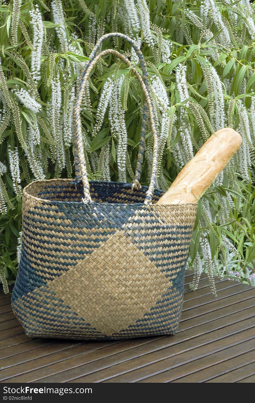 Crispy french bread in a wicker shopping basket left on a table in a graden. Crispy french bread in a wicker shopping basket left on a table in a graden