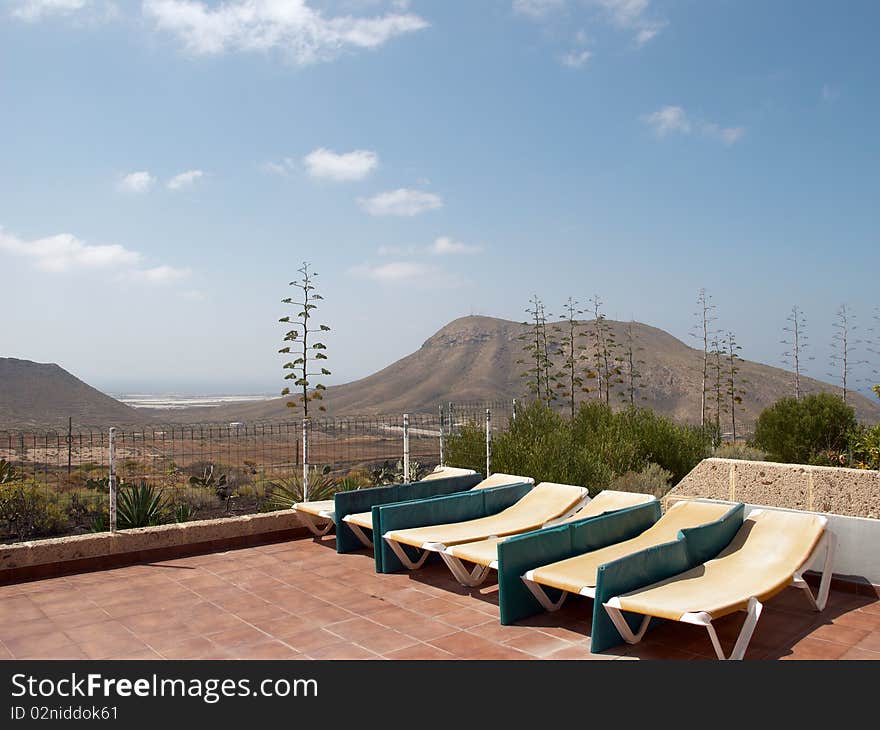 Beach chairs on the background of blue sky and mountains. Tenerife, Canary Islands, Spain.