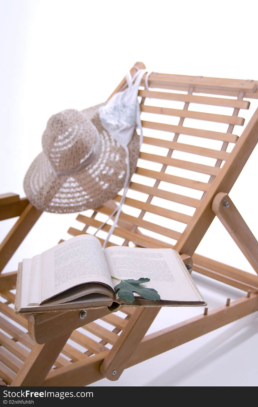 Beach chair, hat, book and a bikini top on a white background. Beach chair, hat, book and a bikini top on a white background.