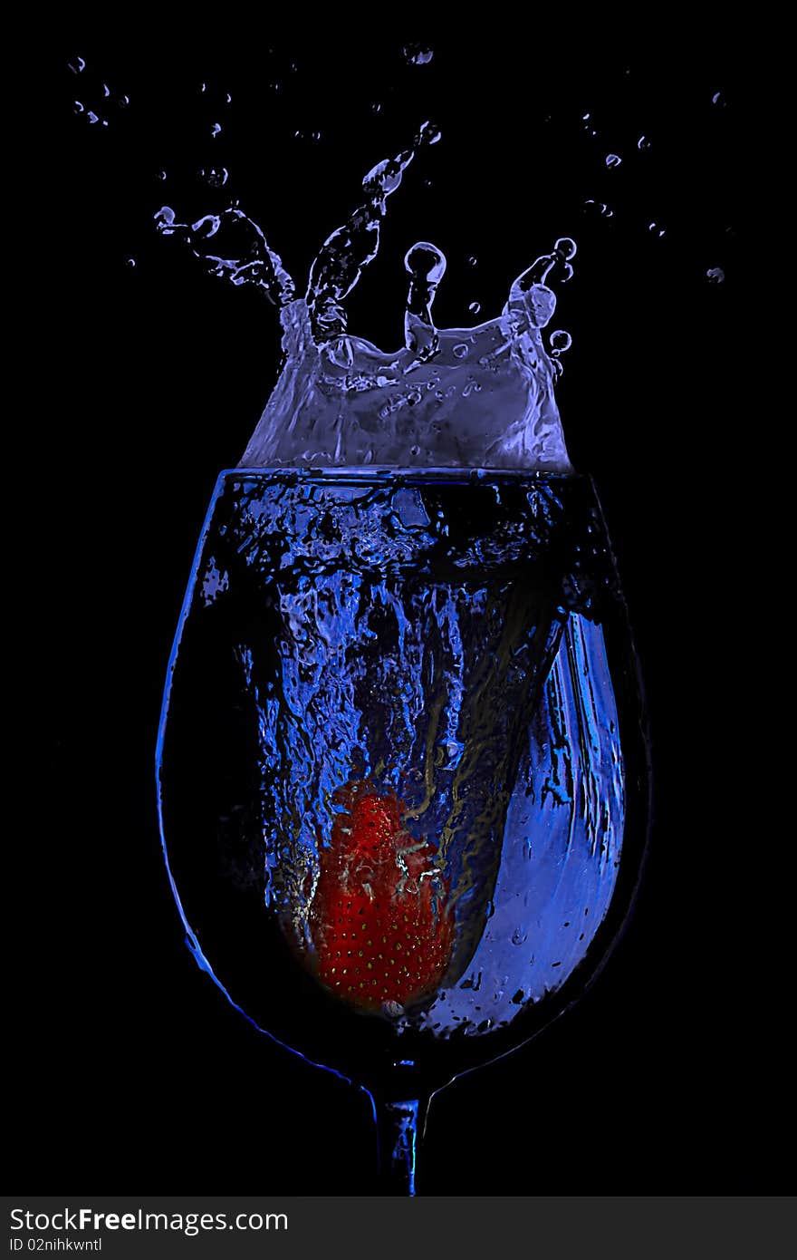 Strawberry splash in a glass of blue water