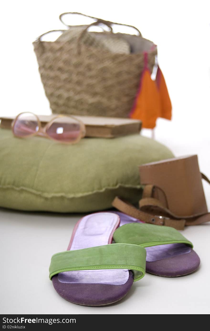 Flip-flops, an old camera, beach bag, sunglasses, book and a  bikini top, arranged on a white background. Flip-flops, an old camera, beach bag, sunglasses, book and a  bikini top, arranged on a white background.