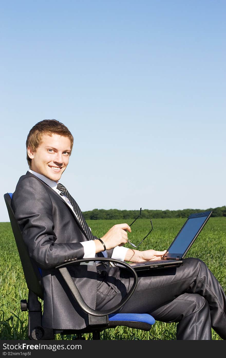 Young businessman with a laptop and glasses on the street. Young businessman with a laptop and glasses on the street