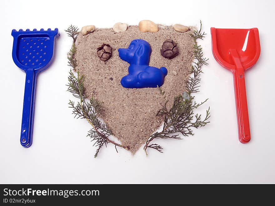 Sand play set -  shovel, rack, mold and a pile of sand, in a shape of seal, on a white background. Sand play set -  shovel, rack, mold and a pile of sand, in a shape of seal, on a white background