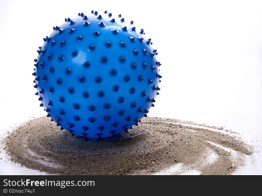 Blue, pointy beach ball, leaving twirling trace in a sand.