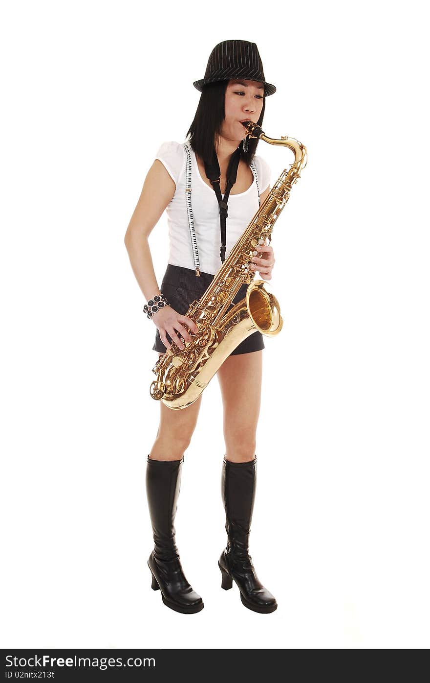 A young Asian woman standing in the studio, playing the saxophone in shorts with suspender and a hat on her black hair, for white background. A young Asian woman standing in the studio, playing the saxophone in shorts with suspender and a hat on her black hair, for white background.