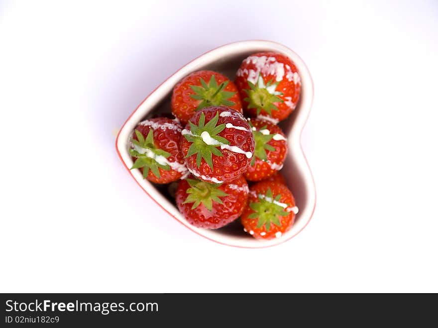 Fresh ripe strawberrys drizzled in cream in a heart shaped dish. Fresh ripe strawberrys drizzled in cream in a heart shaped dish