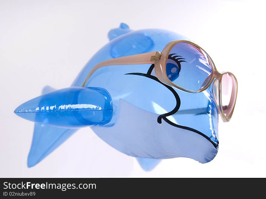 Toy dolphin, wearing sunglasses, on a white background. Toy dolphin, wearing sunglasses, on a white background.