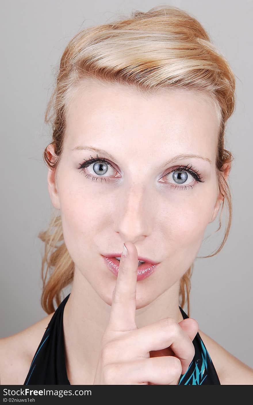 A beautiful blond woman in a green dress standing in the studio and sad be quiet, on light gray background. A beautiful blond woman in a green dress standing in the studio and sad be quiet, on light gray background.