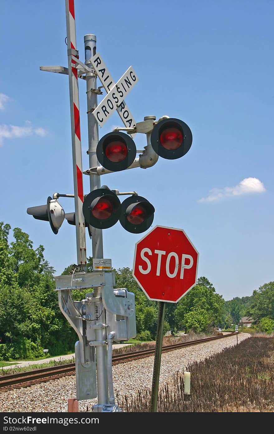 A railroad crossing gate and a stop sign near train tracks