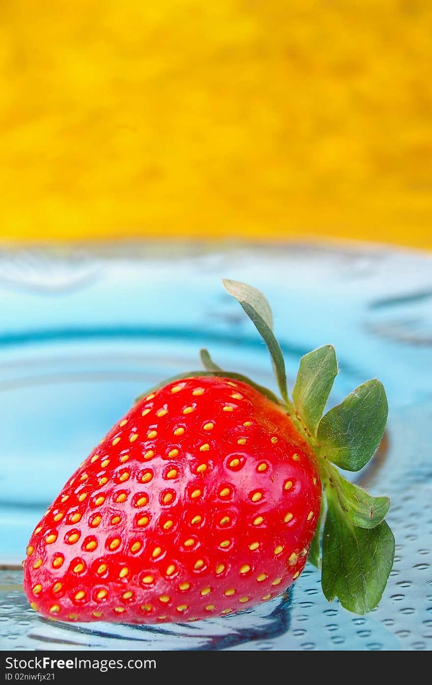 Single strawberry blue glass plate yellow background