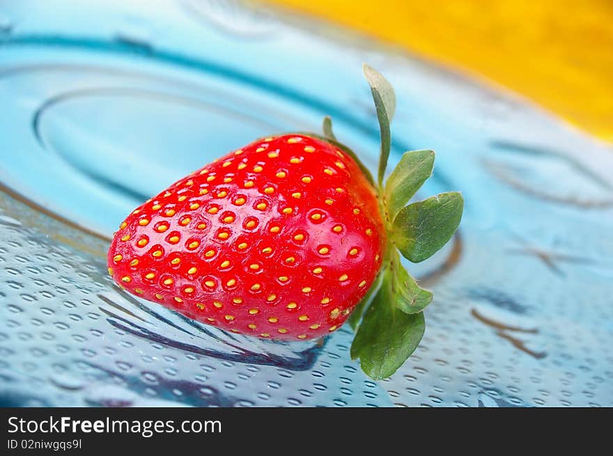 Single strawberry blue glass plate yellow background