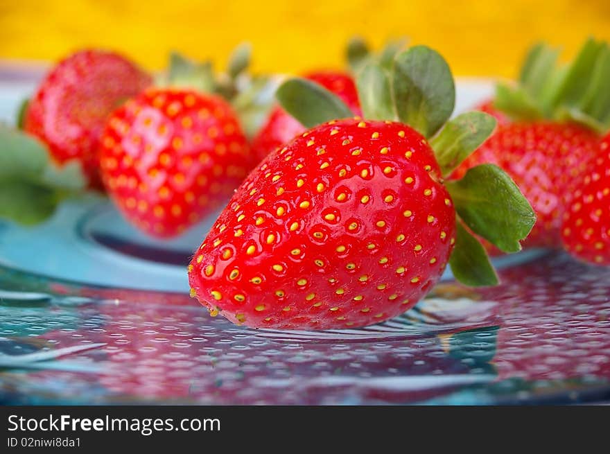 Pile of bright red strawberries on clourful background plate