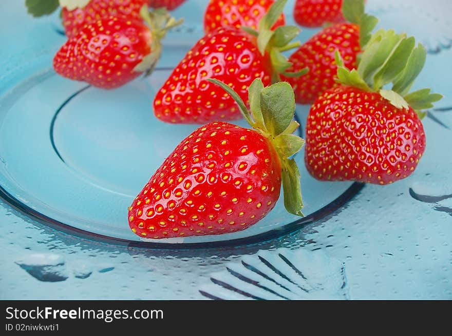 Pile of bright red ripe clean strawberries laid out on ble plate