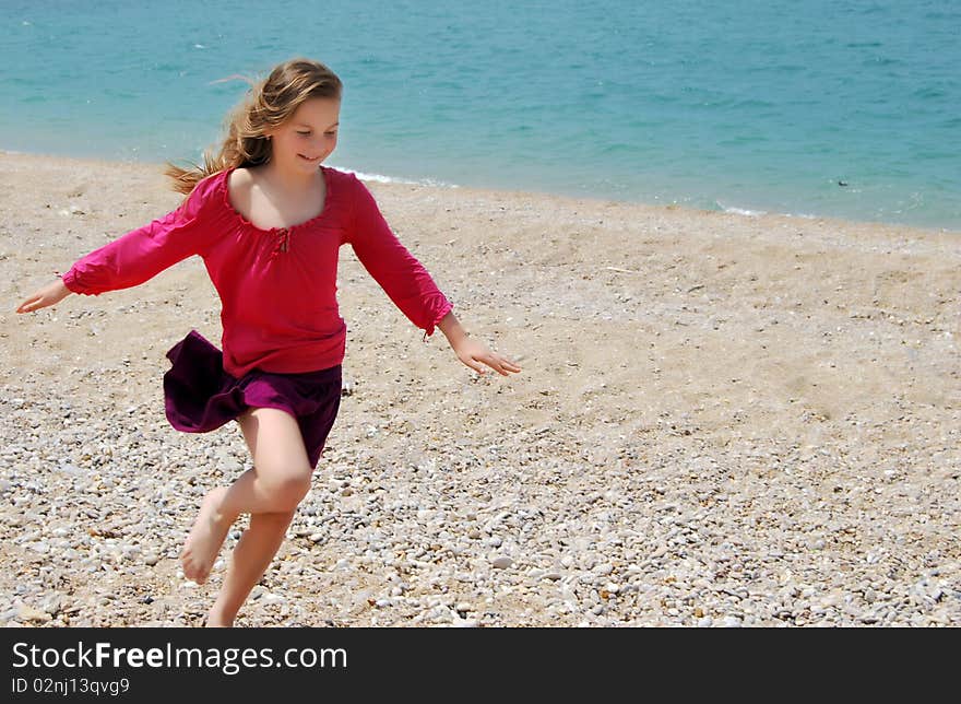 Little happy girl child in pink clothes running on the beach having great holiday fun