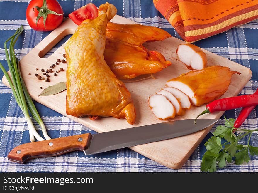 Meat smoked chicken on a wooden cutting board.