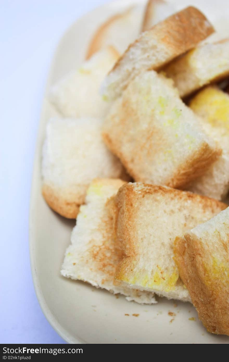 Toast cut in pieces on white plate white background close up