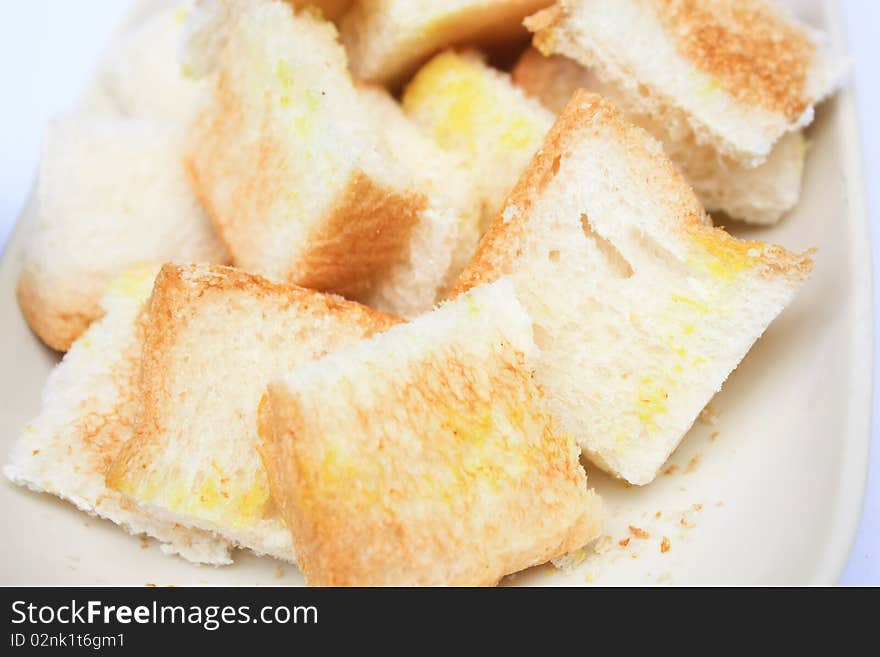 Toast cut in pieces on white plate white background close up