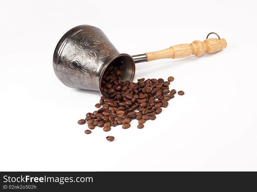 Coffee grains scattered near a coffee pot on a white background. Coffee grains scattered near a coffee pot on a white background