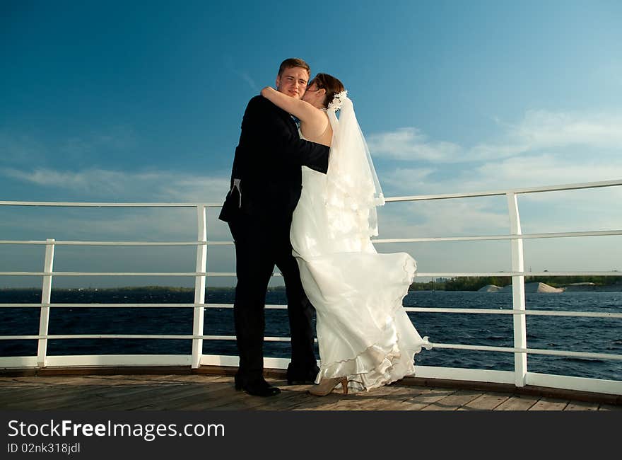 Young beautiful bride embracing each other on the deck near the river. Young beautiful bride embracing each other on the deck near the river