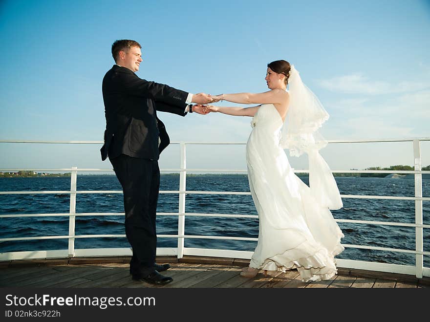 Beautiful young brie and groom holding hands at the deck on the river. Beautiful young brie and groom holding hands at the deck on the river