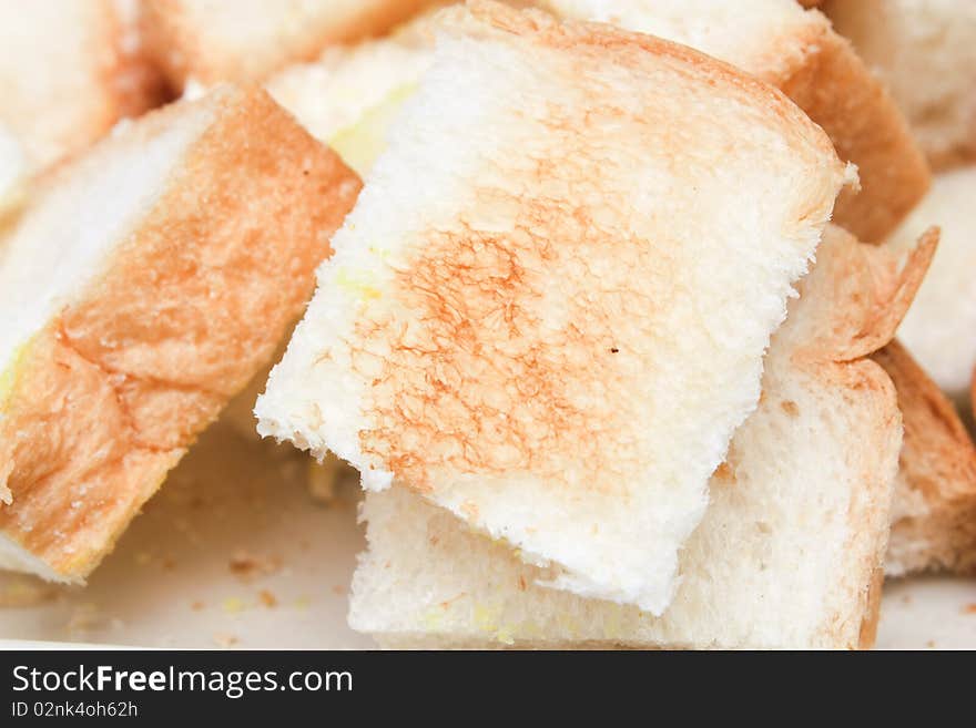 Toast cut in pieces on white plate white background close up