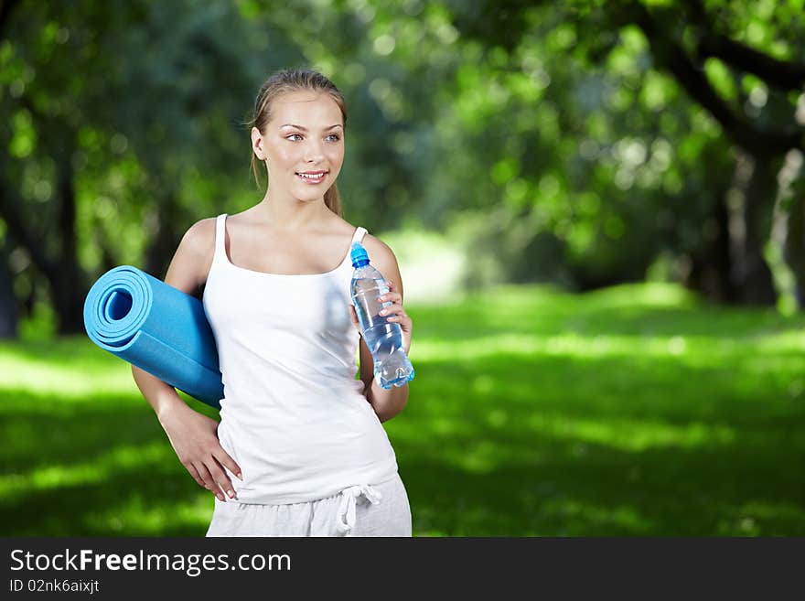 Young girl with a bottle of water and gymnastic mat. Young girl with a bottle of water and gymnastic mat