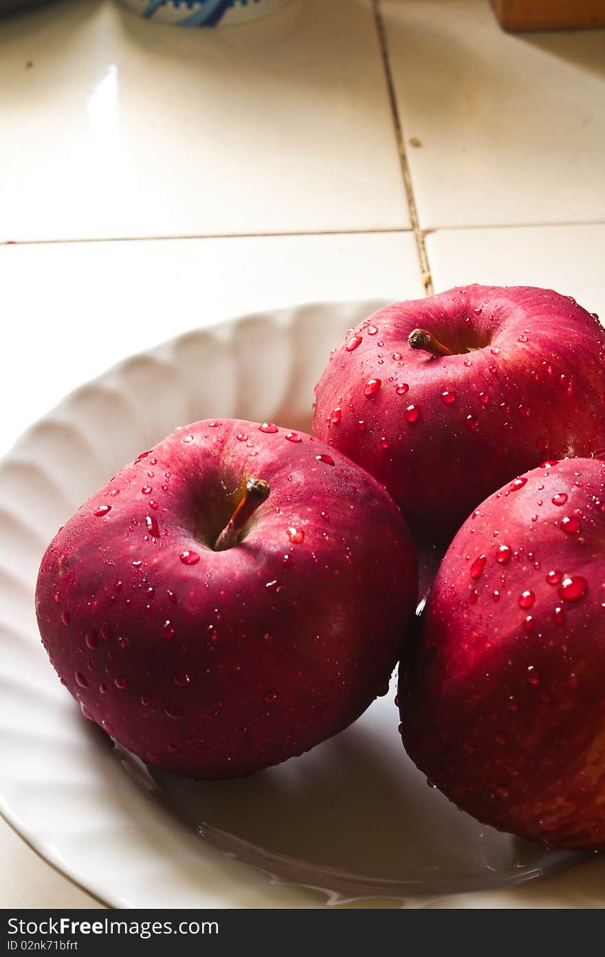 Red apple and drop on white dish