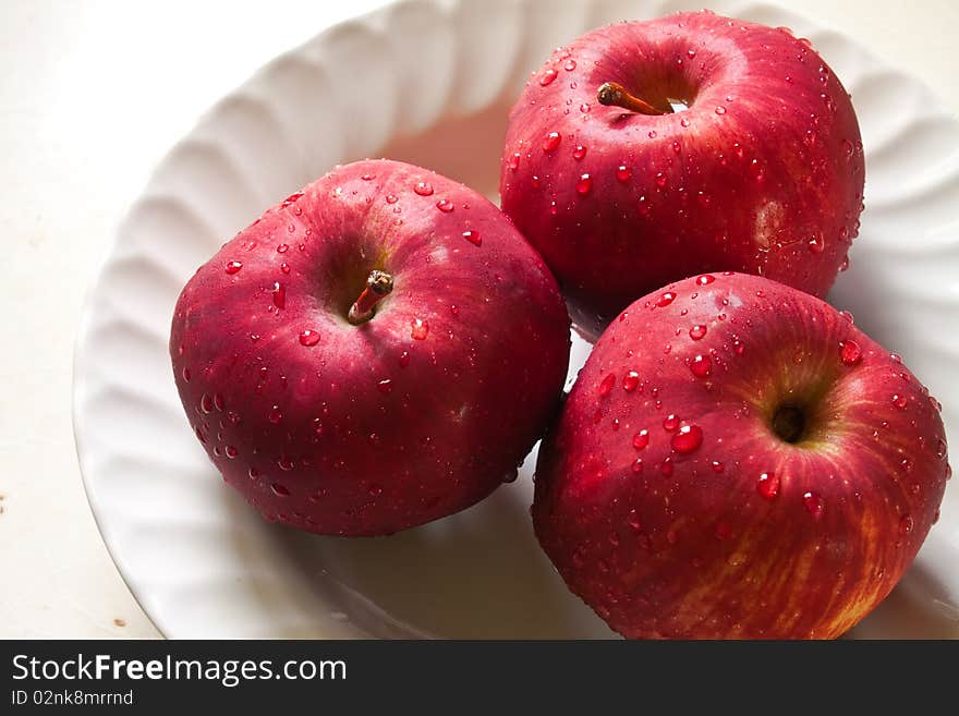 Red apple and drop on white dish