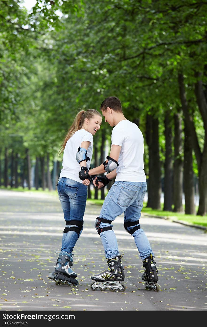 Young couple roller-skating in the park. Young couple roller-skating in the park