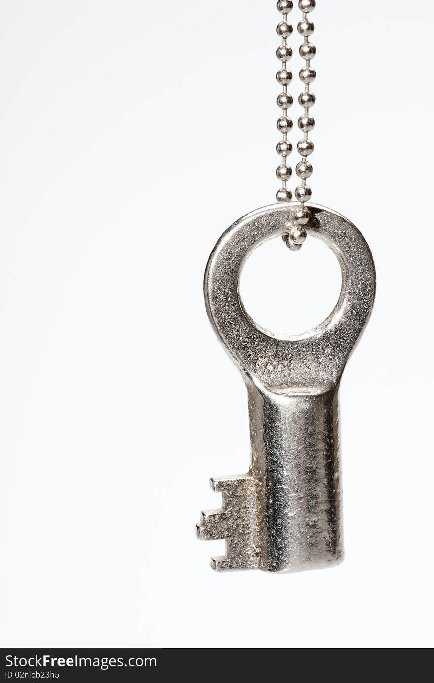 An old, shiny key on a simple metal chain. An old, shiny key on a simple metal chain