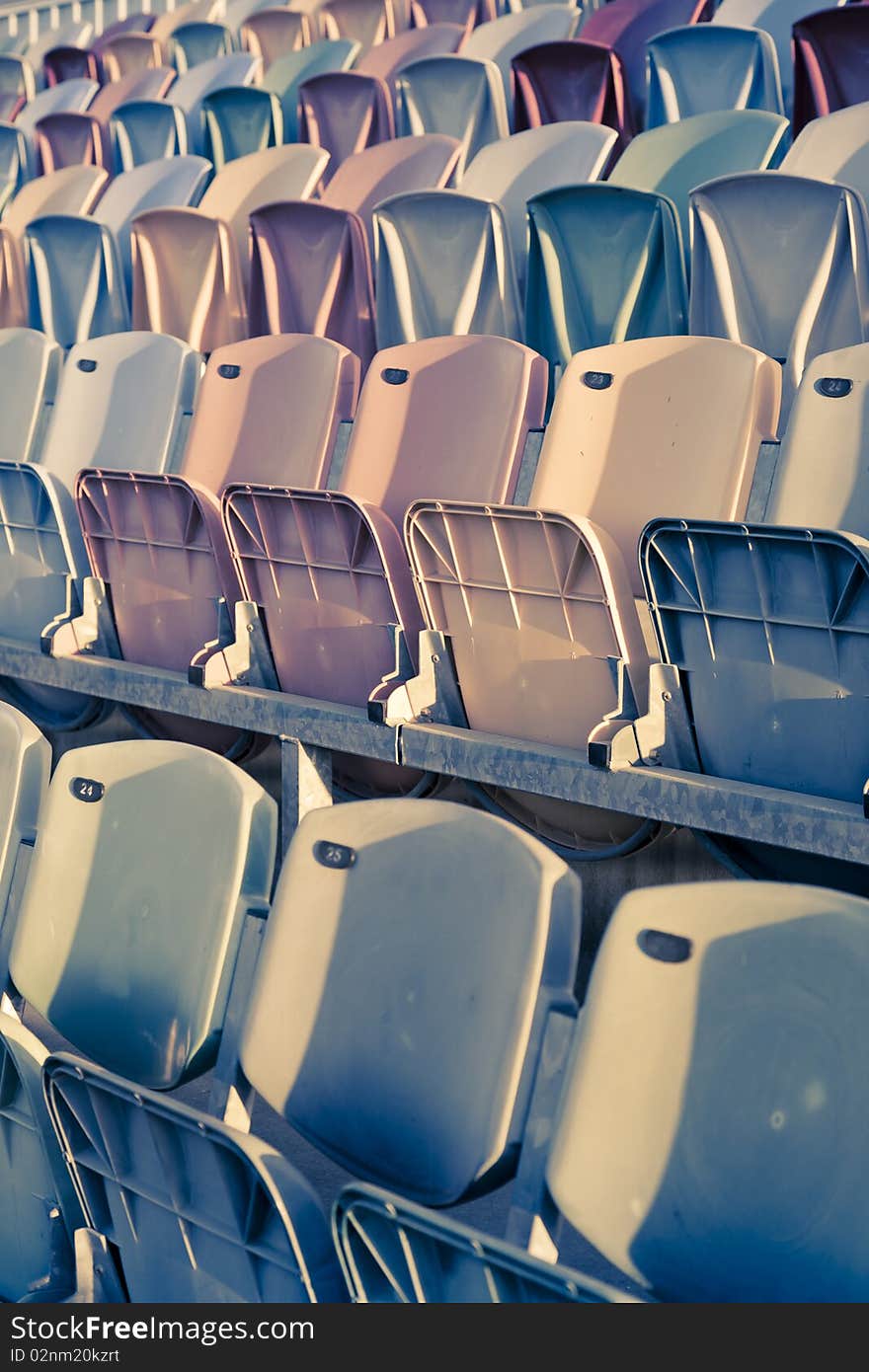 Old colored faded stadium Seats on a row. Old colored faded stadium Seats on a row